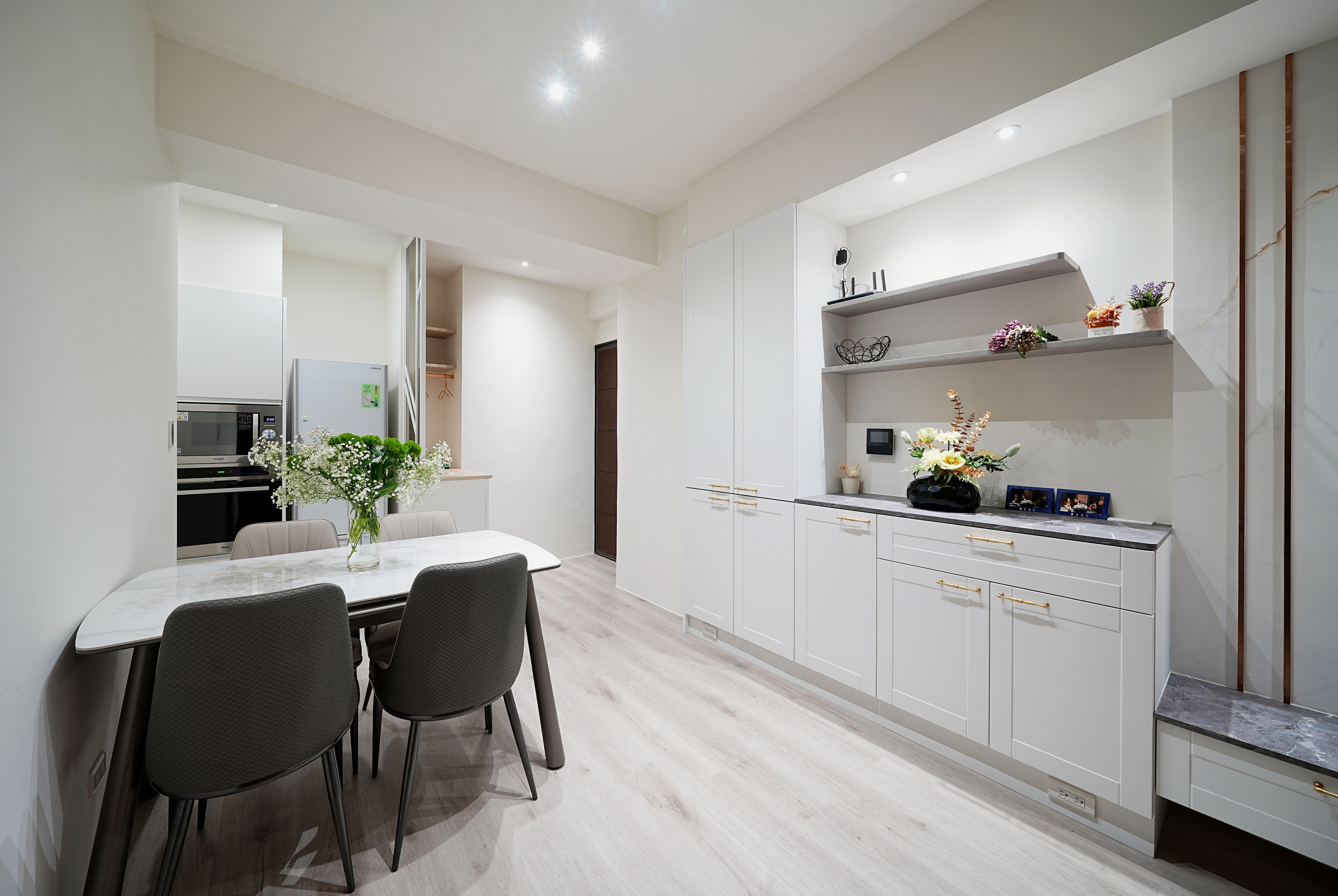 歐式門片廚房系統櫃： 純白線板搭配金屬把手，營造典雅餐飲空間。